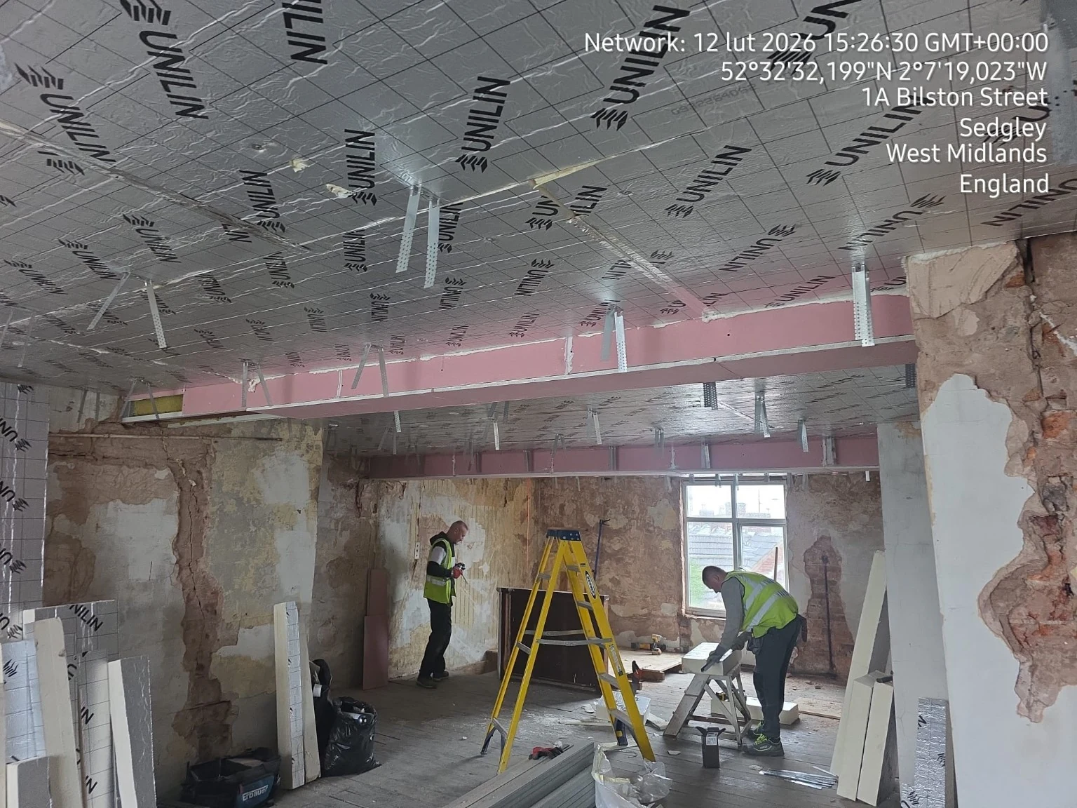 Ceiling works with beams, suspended framing, and insulation within an interior refurbishment