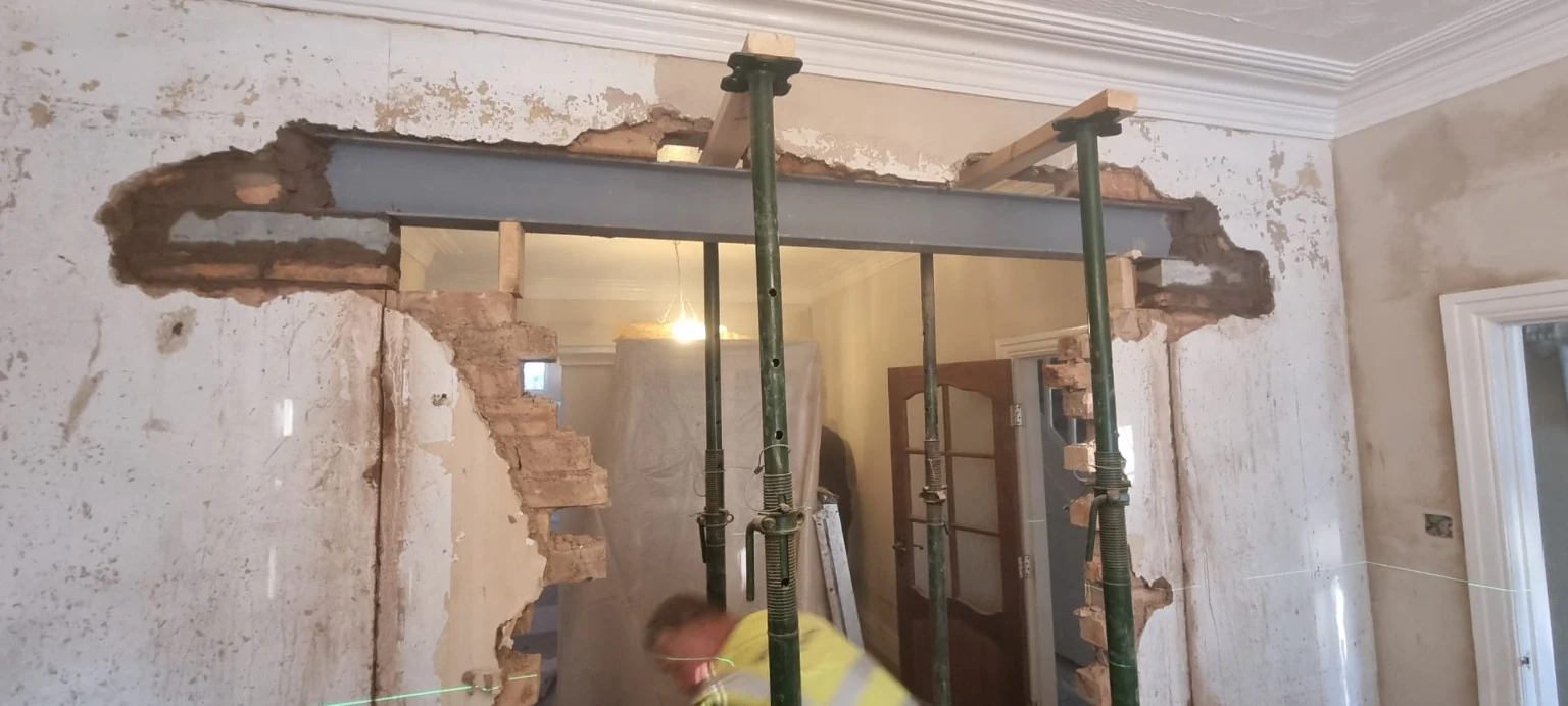 New structural steel beam installed above an opening, with temporary supports
